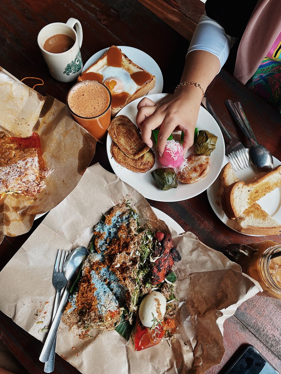Top view of a traditional Malaysian breakfast spread with various local delicacies and drinks in a café.