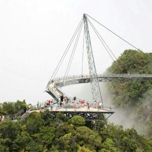 Curved pedestrian bridge on a lush, misty mountainside