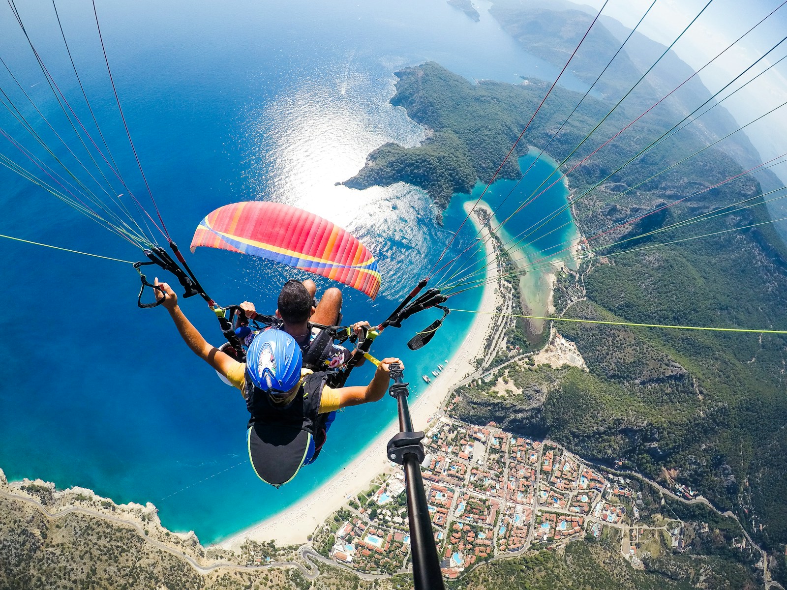 man in blue and black jacket riding on blue and white parachute