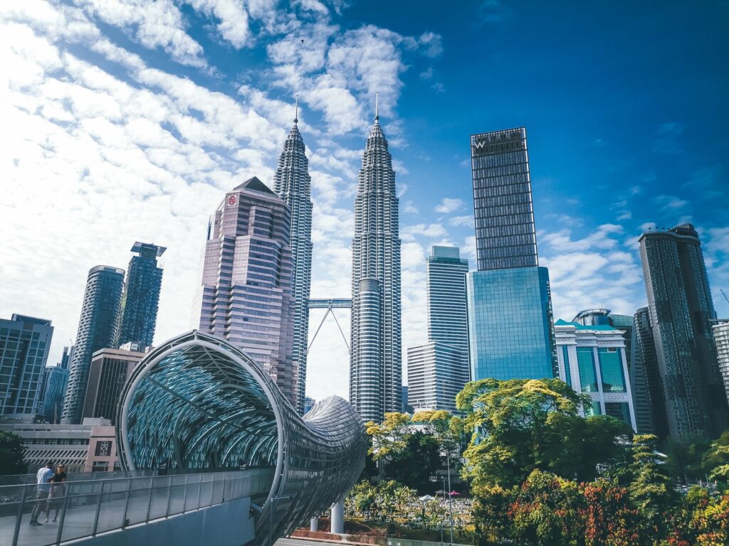 Cityscape with famous Petronas Twin Towers amidst glass contemporary skyscrapers and futuristic pedestrian overpass located in Kuala Lumpur