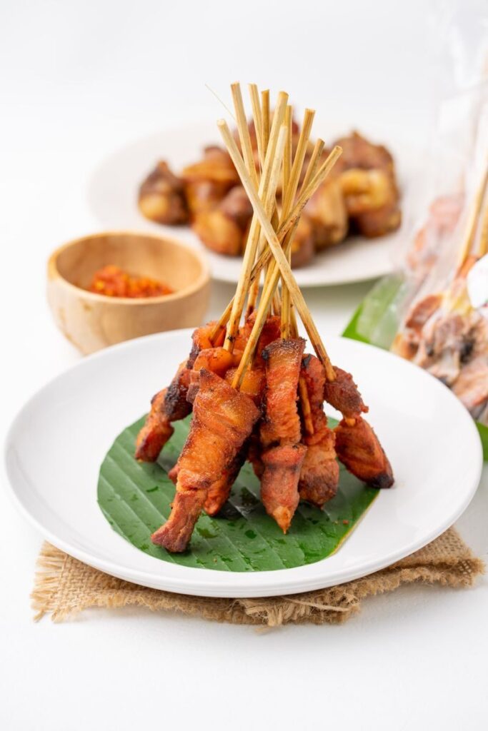Savory Balinese pork skewers served on a banana leaf-lined plate, showcasing traditional flavors.